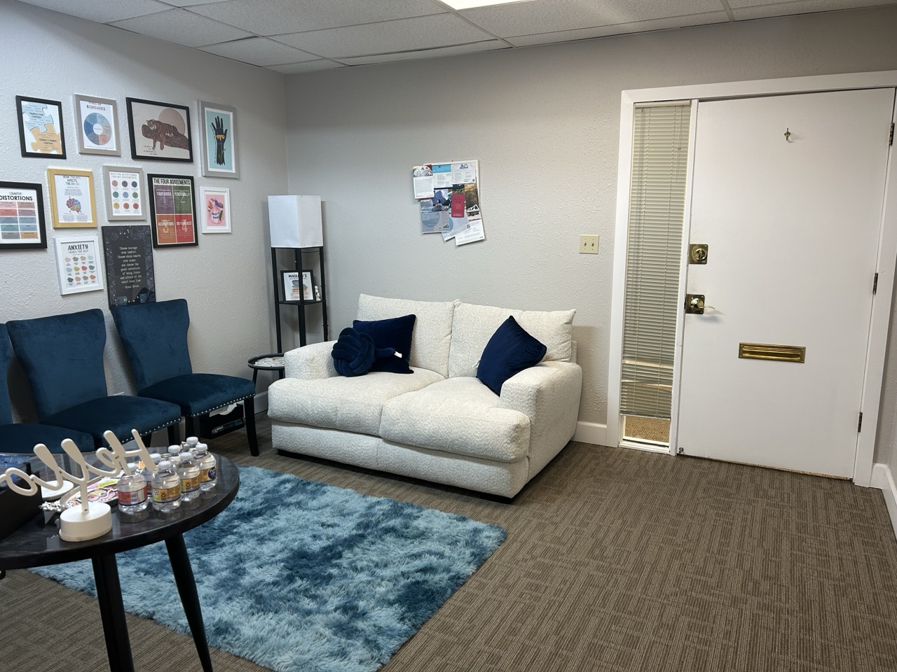 Arvada waiting room with a cream couch, blue chairs, and entry door.